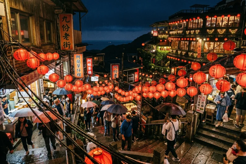 El viaje de chihiro: 5 lugares de japón que debes visitar - jiufen taiwan mito inspiracion ghibli Una vista nocturna de la concurrida calle vieja de jiufen en taiwán, con densas hileras de linternas rojas iluminando las estrechas escaleras y los carteles de las tiendas.