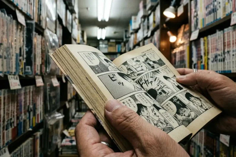 5 autores de manga de terror más perturbadores que junji ito - leer manga fisico nakano broadway tokio Fotografía de unas manos sosteniendo un cómic manga japonés en blanco y negro abierto por la mitad mostrando la textura del papel.