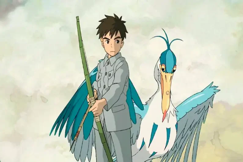 Ranking studio ghibli: las mejores películas de miyazaki - el chico y la garza y el futuro de ghibli Fotograma de animación de un niño joven sosteniendo un arco de madera junto a un hombre pájaro con un enorme pico de garza azul y blanco.