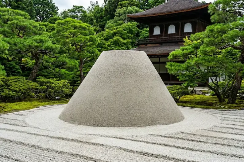 El arte del silencio y la piedra: guía para entender un jardín zen - cono arena mar plateado ginkakuji kioto Fotografía de una montaña de arena blanca perfectamente cónica y plana en la cima, rodeada de un paisaje de arena con surcos horizontales y jardines de musgo.