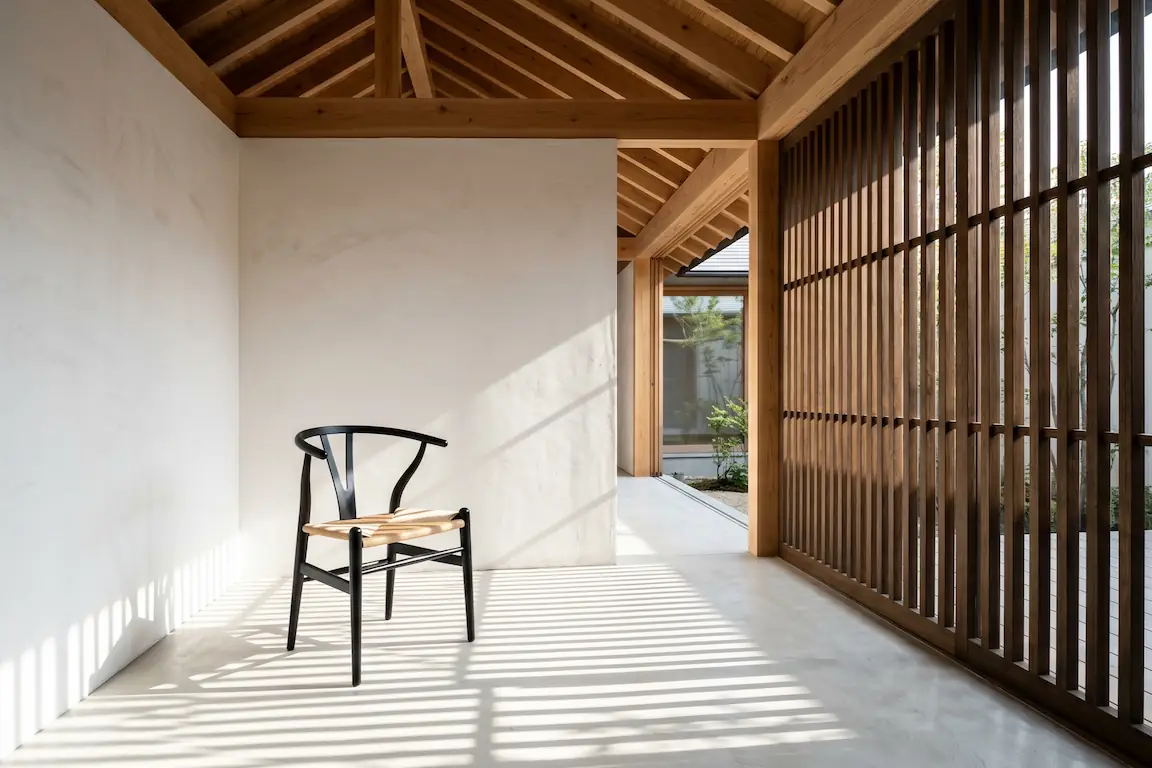 Japandi: el arte de fusionar la serenidad de japón con la calidez nórdica en tu hogar - arquitectura interior japandi luz espacio ma Pasillo o rincón de lectura con paneles de madera, una silla de diseño minimalista y sombras proyectadas por la luz del sol.