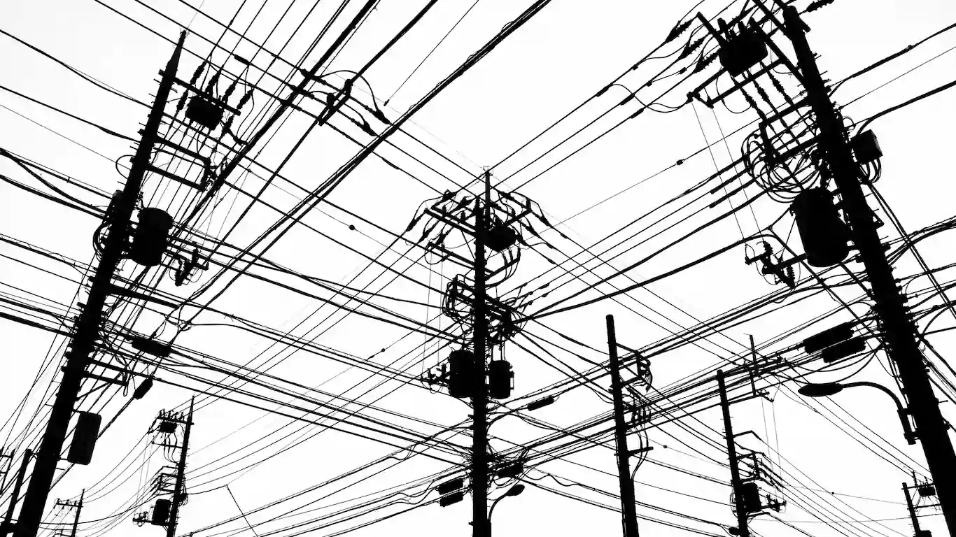 El verdadero origen del cyberpunk anime en japón y el impacto de akira y ghost in the shell - serial experiments lain wired internet Silueta en blanco y negro de un denso entramado de postes de luz, transformadores y cables eléctricos cruzando el cielo.